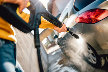 Woman washing her car with pressure washer