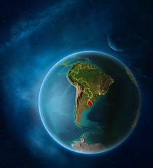 Planet Earth with highlighted Uruguay in space with Moon and Milky Way. Visible city lights and country borders.