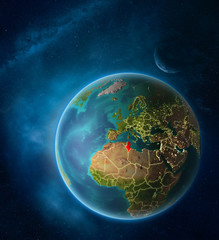 Planet Earth with highlighted Tunisia in space with Moon and Milky Way. Visible city lights and country borders.