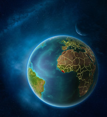 Planet Earth with highlighted Liberia in space with Moon and Milky Way. Visible city lights and country borders.