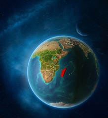 Planet Earth with highlighted Madagascar in space with Moon and Milky Way. Visible city lights and country borders.