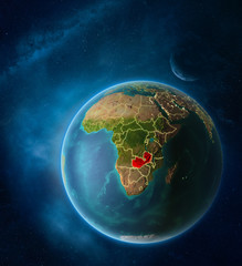 Planet Earth with highlighted Zambia in space with Moon and Milky Way. Visible city lights and country borders.