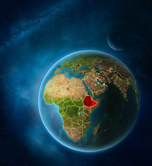 Planet Earth with highlighted Ethiopia in space with Moon and Milky Way. Visible city lights and country borders.