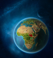 Planet Earth with highlighted South Sudan in space with Moon and Milky Way. Visible city lights and country borders.