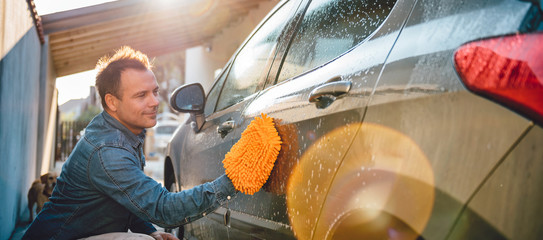 Men washing his car with wash mitt - obrazy, fototapety, plakaty