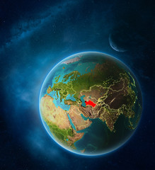 Planet Earth with highlighted Turkmenistan in space with Moon and Milky Way. Visible city lights and country borders.