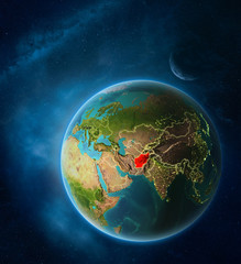 Planet Earth with highlighted Afghanistan in space with Moon and Milky Way. Visible city lights and country borders.