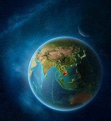 Planet Earth with highlighted Cambodia in space with Moon and Milky Way. Visible city lights and country borders.
