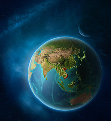 Planet Earth with highlighted Vietnam in space with Moon and Milky Way. Visible city lights and country borders.