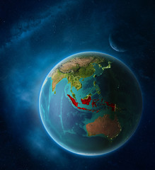 Planet Earth with highlighted Indonesia in space with Moon and Milky Way. Visible city lights and country borders.
