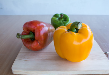Fresh colorful bell pepper cooking on wooden cut board in kitchen table ready for cook