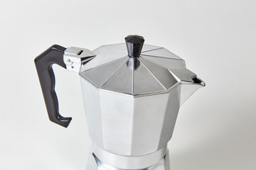 Closeup of metal geyser coffee maker presented on gray background.