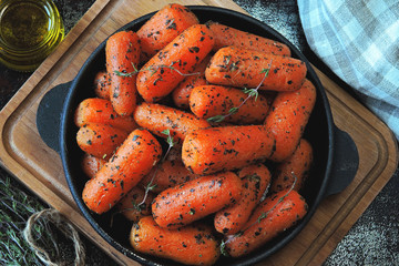 Baby carrots baked with thyme in a cast-iron skillet. Vegan snack.