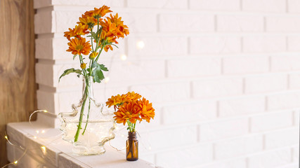 Fototapeta na wymiar Large and small bouquets of orange chrysanthemums in vases in the autumn bright home interior. Comfort and beauty at home