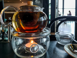 Tea pot above a candle with restaurant background