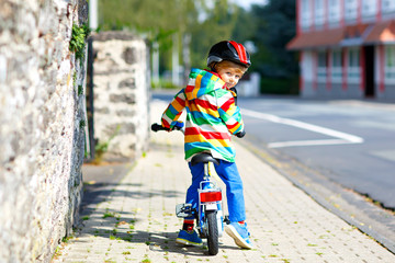 Little cute kid boy on bicycle on summer or autmn day. Healthy happy child having fun with cycling on bike. Active leisure for children. Safe helmet on boy's head. In colorful clothes