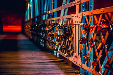 Fototapeta na wymiar Padlocks hanging on a bridge fence as symbol of love and friendship forever. European youth romance culture concept