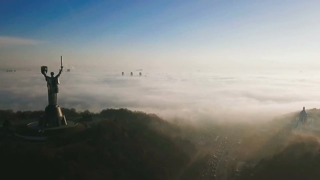 KKiev Ukraine The Motherland Monument USSR heritage. City hills on fog. Beautiful autumn morning. Aerial drone video footage. panoramic view. camera approaches and flies past