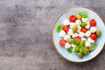 Delicious caprese salad with ripe cherry tomatoes and mini mozzarella cheese balls with fresh basil leaves.