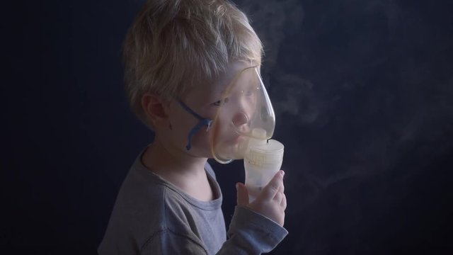 Caucasian blonde boy inhales couples containing medication from inhaler to stop coughing. Medical procedures. Inhaler. Respiratory medicine. Bronchitis, asthmatic health problem. Home treatment breath