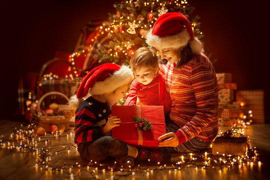 Christmas Family opening Lighting Present Gift Box under Xmas Tree, Happy Mother and Children in Magic Night