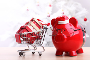 Christmas piggy bank next to a shopping cart full of gift boxes