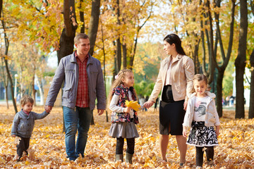 Happy family is in autumn city park. Children and parents. They posing, smiling, playing and having fun. Bright yellow trees.