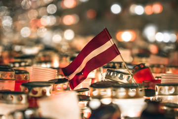Latvian patriots lighting candles as a tribute to fallen freedom fighters. Hundreds of lighten up candles creating cosy atmosphere. Lāčplēša diena - day of independence of Latvia.  - obrazy, fototapety, plakaty
