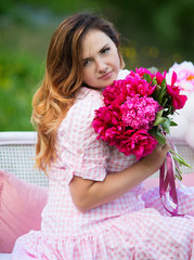 Fototapeta premium A girl in a pink dress is sitting on a sofa in nature.
