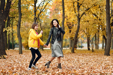 Two happy girls running in autumn city park.