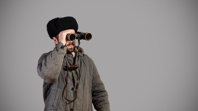 Soviet scout with binoculars keeps track of the situation, studio shot. Great Patriotic War theme