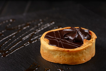 Homemade tart  with dark chocolate on a dark background