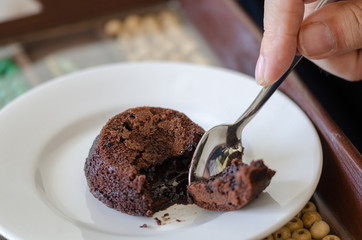 The man is eating hot chocolate cake souffle on white plate.