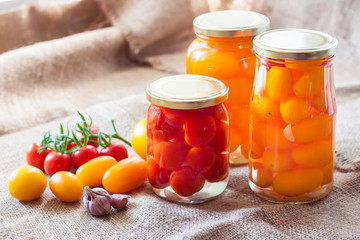 Glass jars with homemade pickled tomatoes, sealed with metal lid