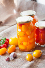Glass jars with homemade pickled tomatoes, sealed with metal lid