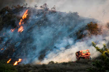 Bulldozer works on Burning Hillside During California Woolsey Brushire