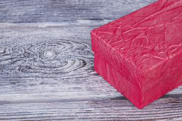 Beautiful gift box on wooden background. Pink textured present box with glossy covering and copy space. Holiday celebration concept.