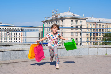 The little happy girl with purchases runs on a meeting to parents.