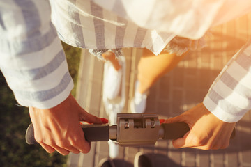 Beautiful female hands hold the scooter by the handles.