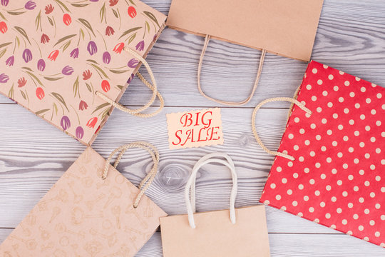 Big sale concept. Paper shopping bags and card with inscription big sale on wooden background, top view.