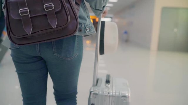 Slow motion - Happy Asian woman using trolley or cart with many luggage walking in terminal hall while going to boarding flight at the departure gate in international airport.