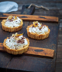 sweet cakes with white cream on a brown wooden board