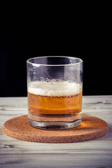 glass of beer, wooden table, foam, black background