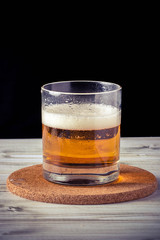 glass of beer, wooden table, foam, black background