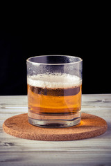 glass of beer, wooden table, foam, black background