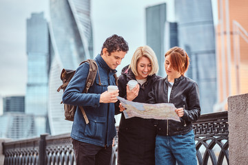 Fototapeta premium Group of tourists searching place on the map in front of skyscrapers