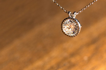 Fototapeta premium Bezel Diamond Pendant Necklace Against Diagonal Wooden Textured Background