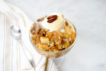 Pecan Cobbler with Vanilla Ice Cream: A dish of southern pecan cobbler in a glass dessert bowl with a spoon