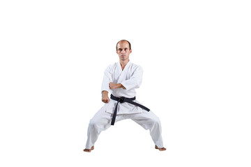 On white background, adult active athlete performs formal karate exercises.
