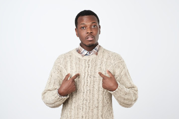 Young african man pointing at himself, making excuses or verbally defending,